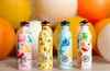 Four colorful children's water bottles with animal and fantasy illustrations are displayed in front of large, out-of-focus spheres. Produktbild-Vorschau