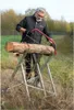 A man is sawing a log on a metal sawhorse outdoors. Anteprima dell’immagine prodotto