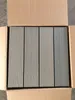 Four grey composite deck boards are arranged vertically inside a cardboard box. Náhled obrázku produktu