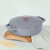 A gray cast iron pot with a pink knob on a wooden board. Anteprima dell’immagine prodotto