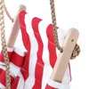 A close-up view of a red and white striped baby swing seat, showing the wooden support and rope attachment. Produktbild-Vorschau