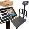 A digital scale with a platform and a display unit, shown with its packaging. Produktbild-Vorschau