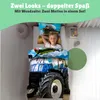 A young boy is lying in bed with a duvet cover featuring a tractor and an airplane. Produktbild-Vorschau