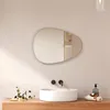 A modern bathroom vanity with a sink, faucet, and an asymmetrical mirror above it. The scene is lit by natural light, casting shadows. Náhľad obrázku produktu