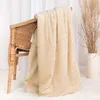 A beige blanket draped over a wicker chair, with dried grass in a vase in the background. Anteprima dell’immagine prodotto