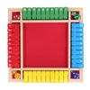 A top-down view of a wooden board game with a red playing surface and numbered tiles in red, green, blue, and yellow. Dice are visible in the corners. Náhled obrázku produktu