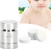 A product shot of a metal tablet press and compressed powder tablets, with a baby in the background. Náhled obrázku produktu