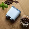 A coffee filter, coffee beans, and mint leaves are arranged on a wooden surface. Produktbild-Vorschau