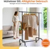 A woman stands next to a clothing rack filled with garments, indoors, with text overlays. Produktbild-Vorschau