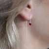 Durchzieher-Ohrhänger an einer Frau mit zarter Silberkette und rotem, herzförmigem Zirkonia – elegant ins Ohr gefädelt, dezent funkelnd. Produktbild-Vorschau