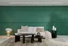 A modern living room with a green textured wall, a white sofa, coffee tables, and a floor lamp. Produktbild-Vorschau