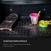 The image shows the interior of a car trunk with a skateboard, a bucket, and sand toys on a black mat. Text overlays describe the product's temperature resistance. Produktbild-Vorschau