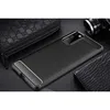 A black phone case with carbon fiber accents is displayed on a dark surface, alongside a black leather wallet and a camera lens. Podgląd zdjęcia produktu