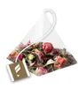 A single pyramid tea bag filled with loose leaf tea and dried fruit/flower pieces, with a small tag attached. Produktbild-Vorschau