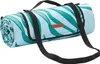 A rolled-up picnic blanket with a tropical leaf pattern and black straps. Produktbild-Vorschau