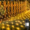 A net light string is draped over a wooden fence and grass, with a power plug visible in the foreground. Náhled obrázku produktu