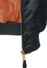 A close-up view of the lower part of a black bomber jacket, showing the zipper and the orange lining. Náhľad obrázku produktu