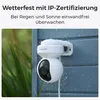 A white security camera is mounted on a blue wall, with water droplets on the camera and wall, suggesting it is weatherproof. Produktbild-Vorschau