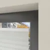 A close-up view of a window with a pleated blind and a view of a street with buildings and trees in the background. Produktbild-Vorschau