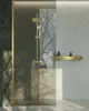 A modern bathroom with a gold shower fixture and a gold shelf with bottles. Produktbild-Vorschau