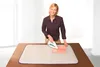 A woman is ironing a piece of fabric on a table with an ironing mat. Produktbild-Vorschau