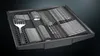 A close-up view of a dishwasher cutlery basket filled with silverware and a spatula. Produktbild-Vorschau