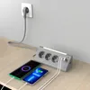 A power strip with multiple outlets and USB ports is shown on a wooden desk, with two smartphones charging. Produktbild-Vorschau
