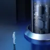 A miniature figure of a person stands on a reflective blue surface, looking up at a large, illuminated cylindrical object with visible internal circuitry and the 'Baseus' logo. Náhľad obrázku produktu