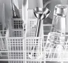 Close-up of kitchen utensils and glasses in a dishwasher basket. Produktbild-Vorschau