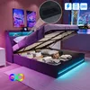 A bed with its storage compartment open, showing folded linens and a bag. The bed has LED lighting around its base and headboard, and there are abstract art pieces on the wall. Produktbild-Vorschau