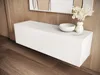 A white floating cabinet with decorative items on top, set against a wood-paneled wall and wooden floor. Náhľad obrázku produktu