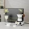A coffee maker set displayed on a white surface with a gift box in the background. Produktbild-Vorschau