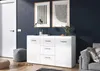 A modern living room scene featuring a white sideboard, artwork, and a sofa. Produktbild-Vorschau