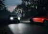 Two cars driving on a road at night, one with headlights on. Produktbild-Vorschau