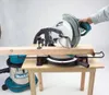 A person is using a miter saw to cut a piece of wood, with a vacuum cleaner attached. Podgląd zdjęcia produktu