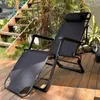 A black reclining lounge chair is set up on a wooden deck in a garden setting, with stairs and lush greenery in the background. Voir les images du produit