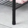 A close-up view of the black metal leg of a towel rack, showing a screw and a black cap at the bottom. A pink towel is visible on the shelf above. Voir les images du produit