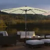 An outdoor patio set with a large umbrella, chairs, and a coffee table, situated on a wooden deck overlooking a lake at dusk. Náhľad obrázku produktu