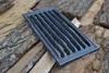 A cast iron grill grate rests on a pile of firewood. Anteprima dell’immagine prodotto