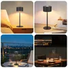 Collage of four images showing a black LED table lamp in different settings: on a bedside table, on a desk, on an outdoor table at night, and on a dining table in a restaurant. Náhľad obrázku produktu