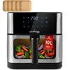 A silver and black air fryer with a transparent window showing vegetables inside, placed on a white background. There are also four brown paper liners for the air fryer at the top left. Produktbild-Vorschau