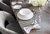 A formal dining table setting with plates, cutlery, and a floral arrangement. Voir les images du produit