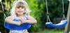 A young girl is sitting on a blue swing in a garden. Anteprima dell’immagine prodotto