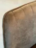 A close-up, detailed shot of the quilted texture and stitching on the back of a brown upholstered chair. Produktbild-Vorschau