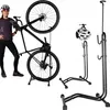 A woman is standing next to a bicycle mounted on a stand. There are also separate images of bicycle stands and a helmet. Náhľad obrázku produktu