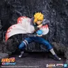 A figurine of Minato Namikaze from Naruto Shippuden, posed in a dynamic stance with a blue energy sphere in his hand, set against a rocky, dark background. The Naruto Shippuden logo is visible in the bottom left corner. Náhled obrázku produktu