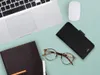 A flat lay of a laptop, mouse, glasses, wallet, and notebook on a light blue background. Náhled obrázku produktu