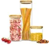 Three glass storage jars with bamboo lids filled with different types of pasta and some tomatoes on the side. Produktbild-Vorschau