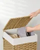 A person is putting clothes into a wicker laundry basket. Podgląd zdjęcia produktu