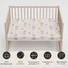 A crib with a fitted sheet featuring a space-themed pattern of bears and rockets. Produktbild-Vorschau